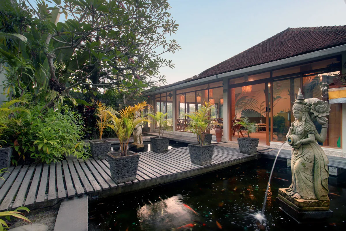 Hesa Downtown koi pond walkway with potted palms and Balinese statue, Ubud Bali