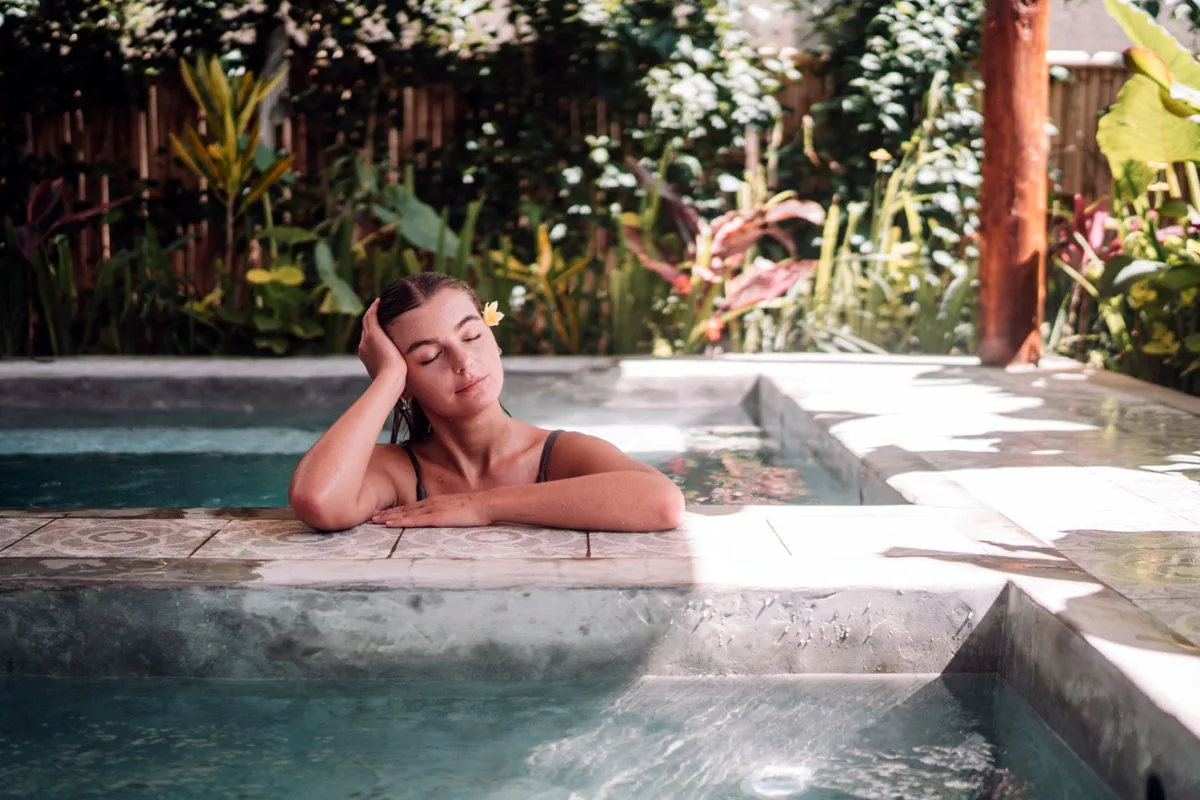Hesa Spa Sandat woman relaxing in plunge pool with frangipani in hair, Ubud Bali